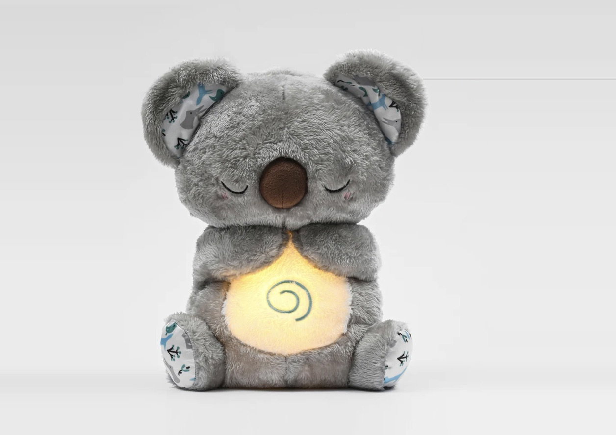 The Hugease koala, a grey plush toy with a softly glowing belly, photographed on white