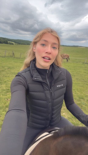 The picture that went in: a young woman in a black vest, riding a horse through a field